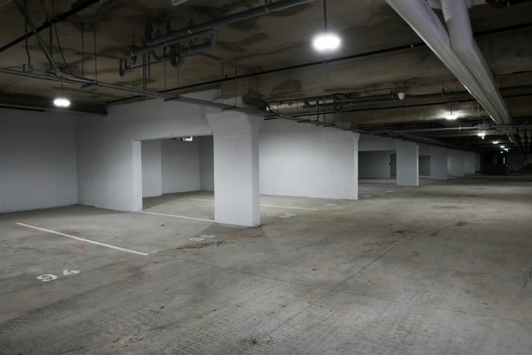 M&M Painting Contractors painting concrete walls in a parking garage.