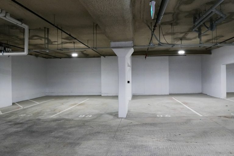M&M Painting Contractors painting concrete walls in a parking garage.
