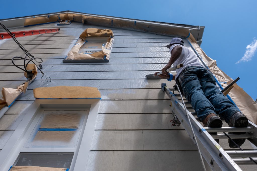 M&M Painting Contractors painting the exterior siding of a residential home.