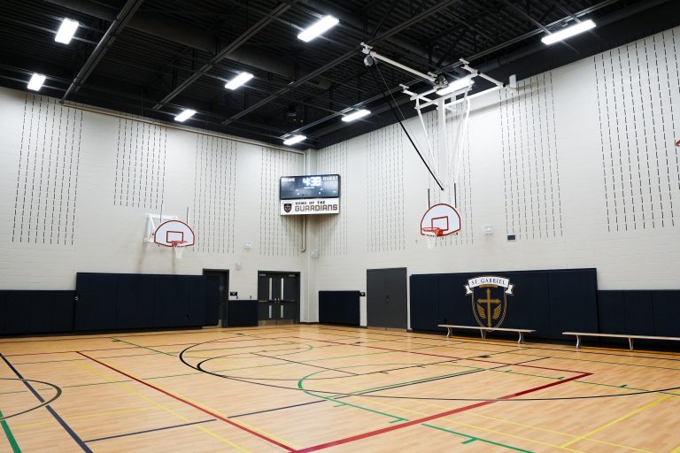 M&M Painting Contractors painting the gymnasium in a school building.
