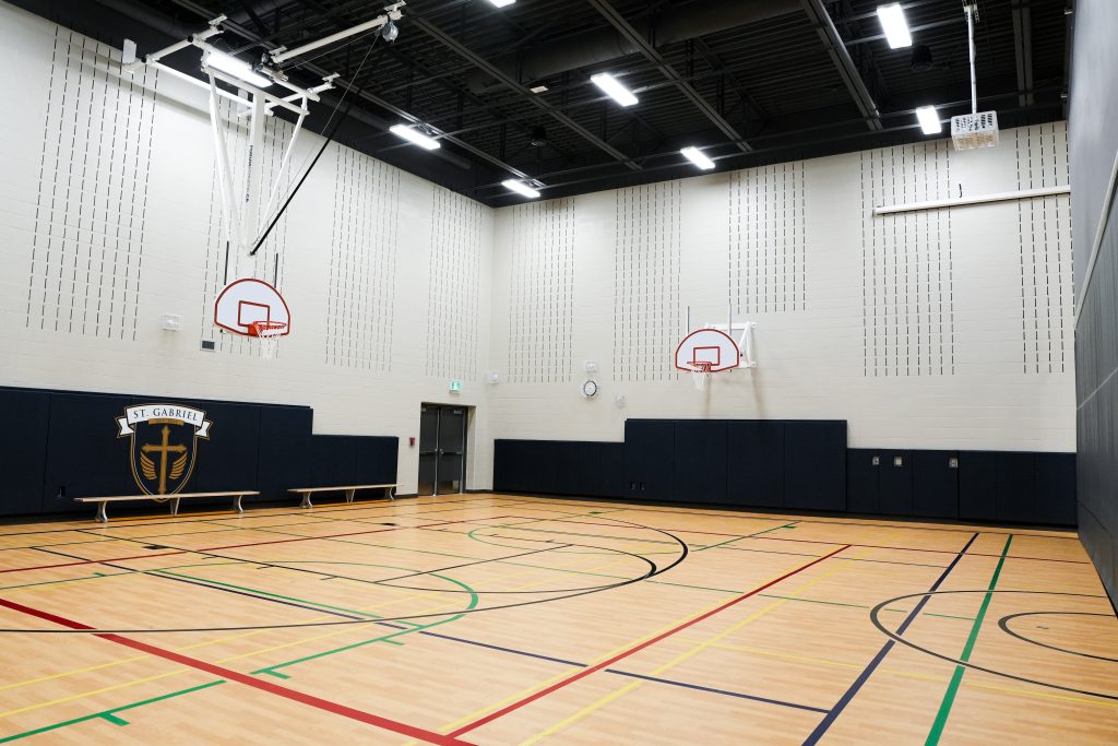 M&M Painting Contractors painting the gymnasium in a school building.