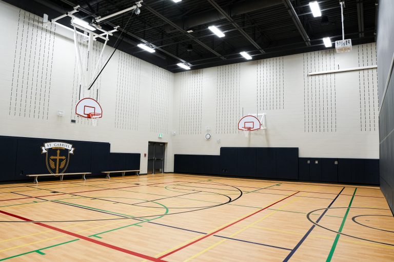 M&M Painting Contractors painting the gymnasium in a school building.